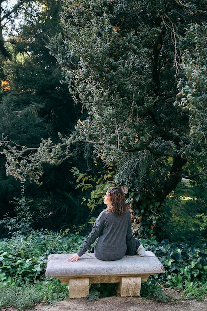 A woman practices mindful walking meditation in a park, focused on each step. She is surrounded by lush greenery and dappled sunlight, enhancing the sense of calm and connection with nature.