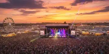 Festivals de Musique France 2026 : Impact Social et Étude de Cas Vue aérienne d'un festival de musique français bondé au coucher du soleil, avec une scène illuminée et une foule enthousiaste.